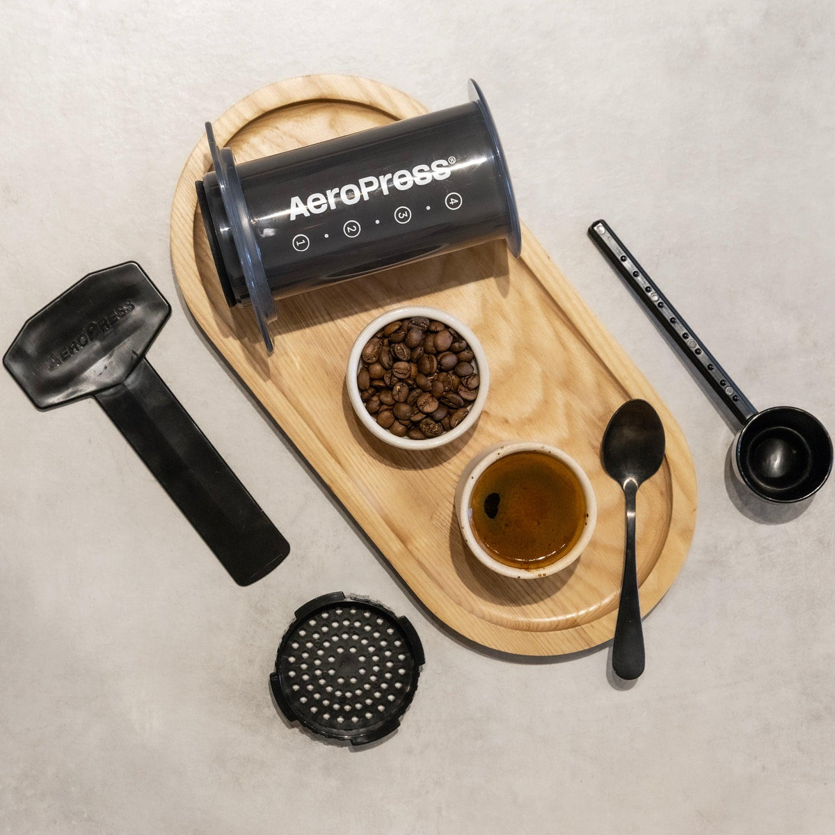 AeroPress z ziarnami kawy na tacy, obok osprzet